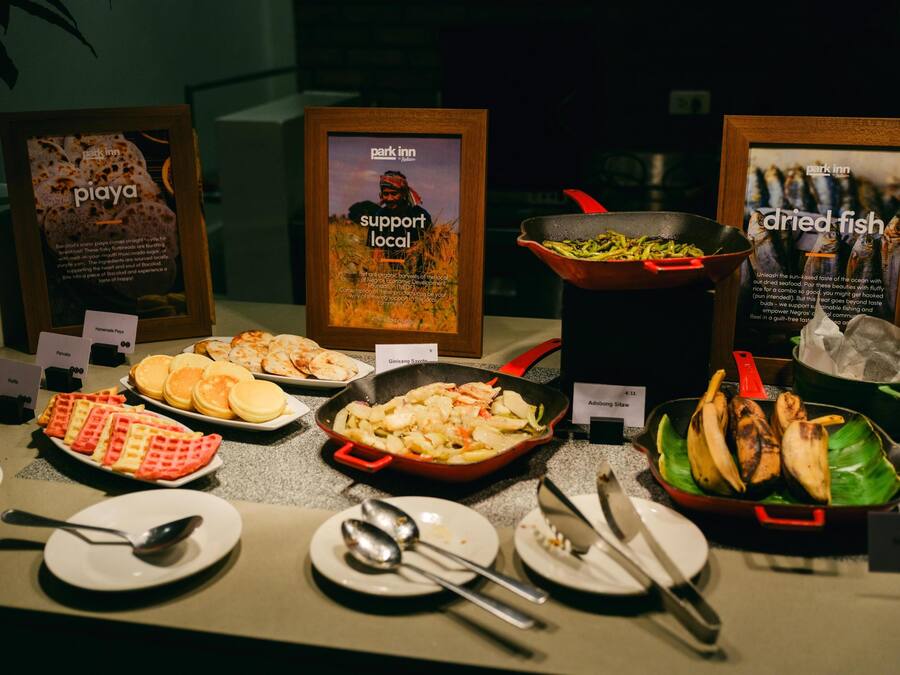 A buffet with various dishes, including waffles, a skillet with vegetables, and a bowl of bananas.