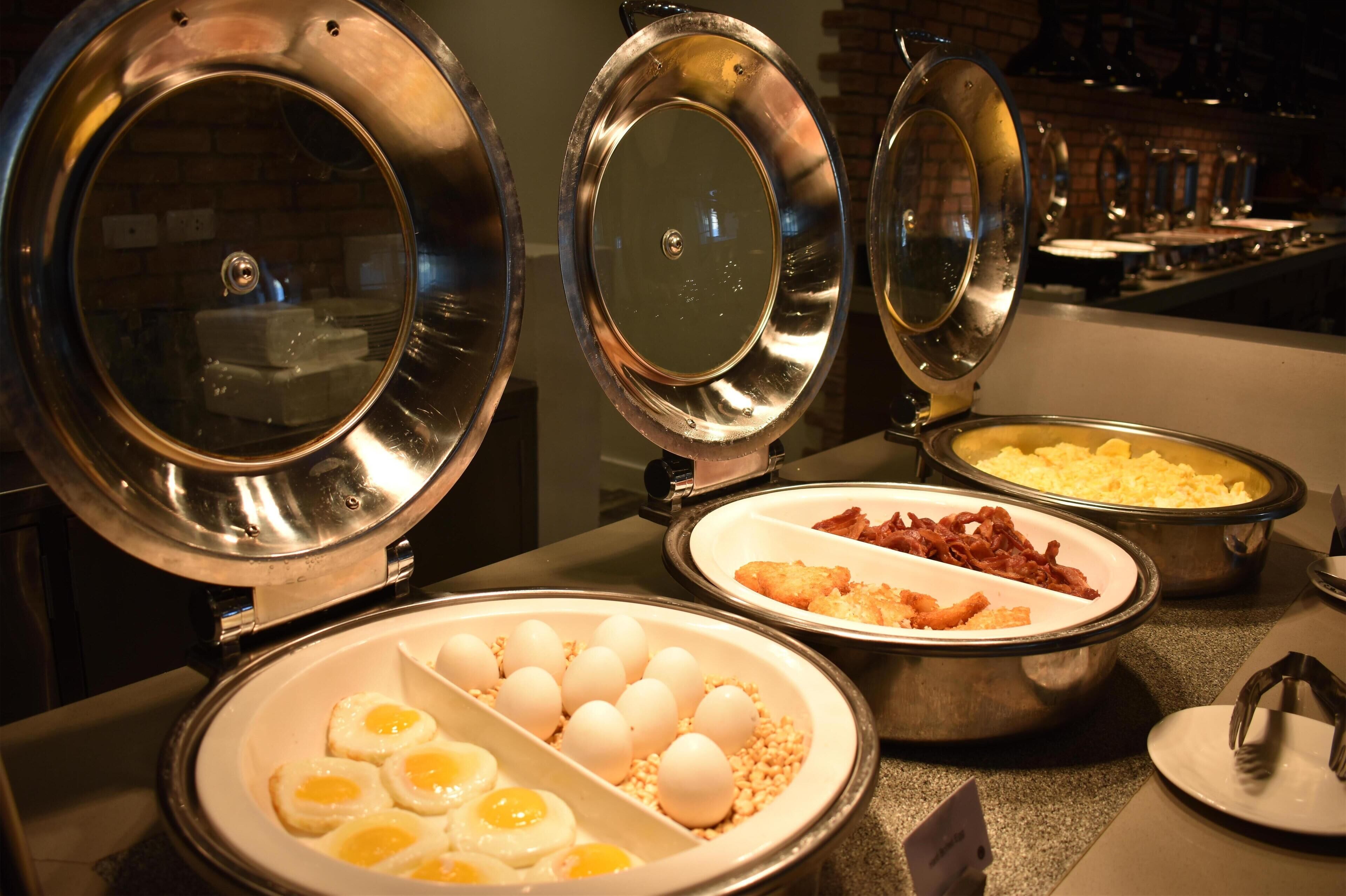 A buffet with various food items including eggs, bacon, and scrambled eggs.
