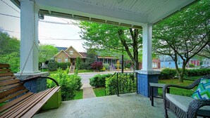 A covered porch with a bench, a wicker chair, and a small table.