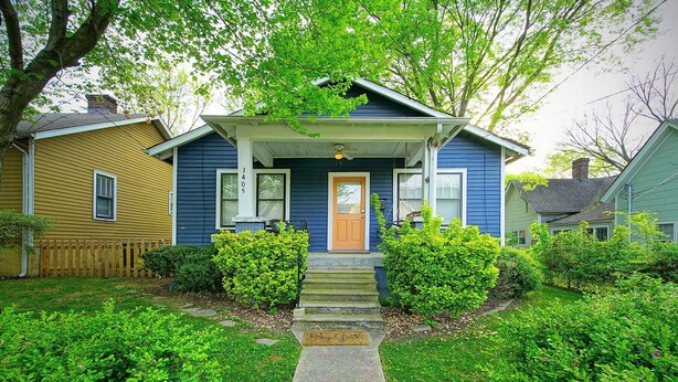 A two-story house with a front porch, a front door, and a mailbox.