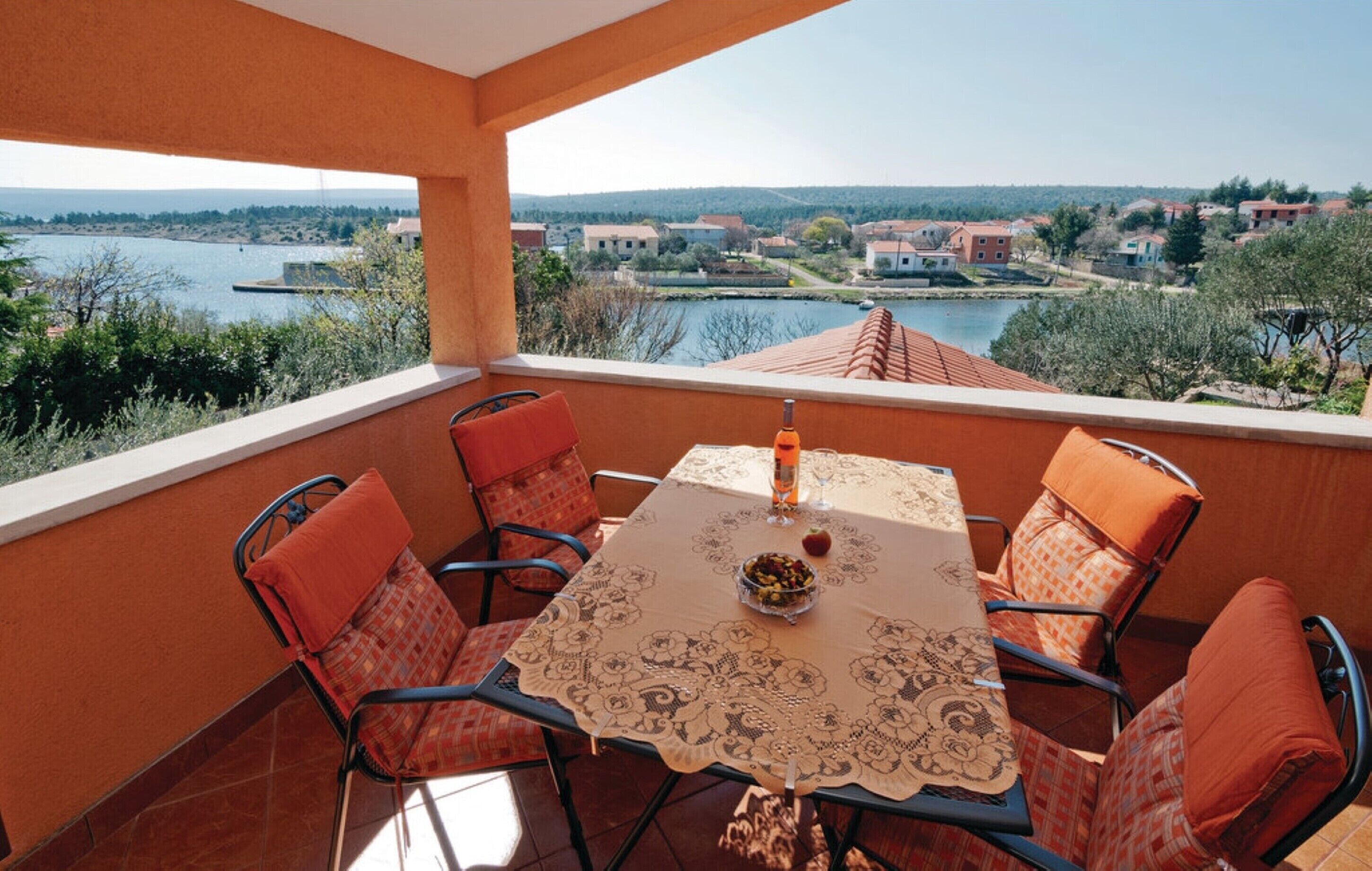 A balcony with a table and chairs, overlooking a river and buildings.