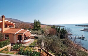 Relax by the serene lake with a patio area and a wooden dock extending into the water.