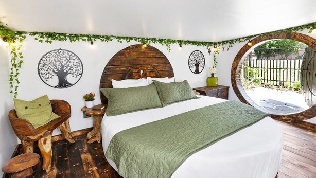 Une pièce circulaire comprenant un lit, des meubles en bois et des œuvres d’art murales.