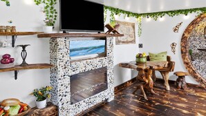 Un salon chaleureux avec une cheminée en pierre, des étagères en bois et un téléviseur.