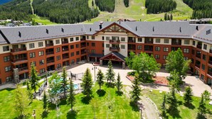 Suuri, useita kerroksia käsittävä hotelli, jossa on keskeinen sisäpiha, ja sen ympärillä on vehreää kasvillisuutta sekä taustalla kohoava vuoristo.