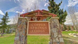 Majatalon kyltti, jossa lukee ”Copper Springs Lodge”, ja sen ympärillä on kivipilareita sekä yläpuolella puinen rakenne.