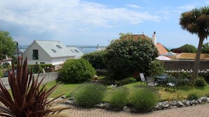 A residential property with a paved patio, a lawn, and a view of the sea. - Robin Hill (St Austell)