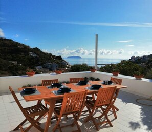 A wooden table with chairs on a terrace overlooking a coastal view. - Villa with a garden and 2 private terraces in the center of Ponza.   (Ponza)