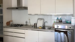 Une cuisine moderne avec des armoires blanches, une hotte en acier inoxydable, un four encastré et un lave-vaisselle.