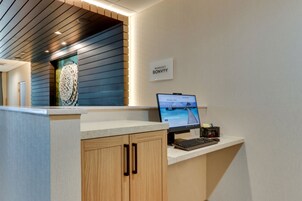 Un mostrador de recepción con un monitor de computadora, un letrero que dice "Marriott Bonvoy" y un elemento decorativo en la pared.