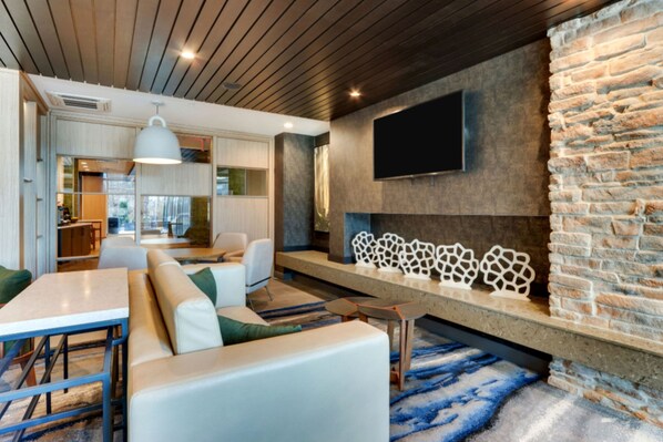 A modern living room with a stone accent wall, a flat-screen TV, and a fireplace.