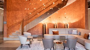 A modern interior with a staircase, a seating area, and a reception desk. - AC Hotel by Marriott Wuerzburg (Würzburg)