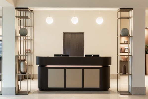 Un comptoir d’accueil au design minimaliste, entouré d’étagères où sont disposés des objets décoratifs.