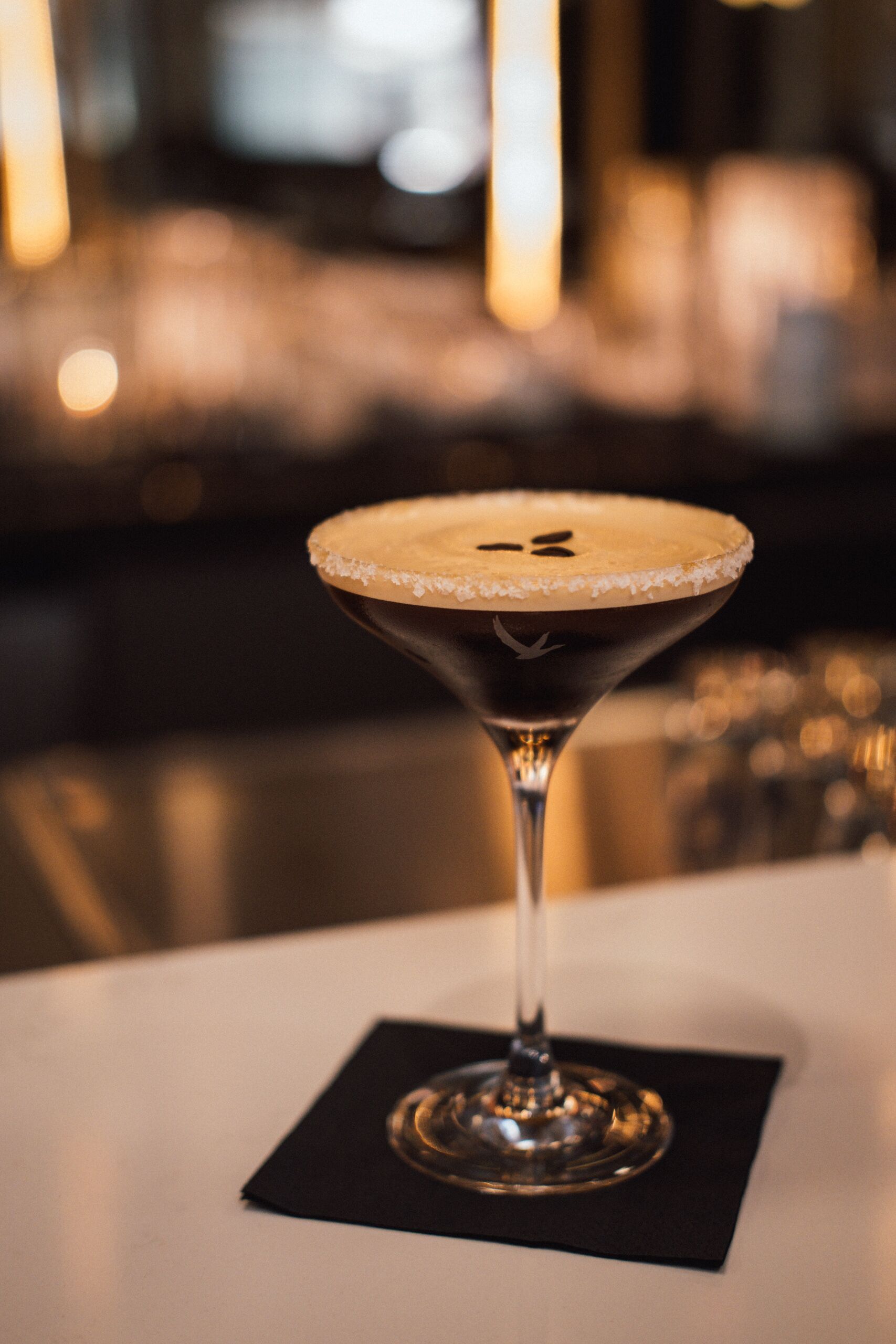 Ein Martini-Glas mit Salzrand auf einem weißen Tisch.