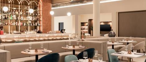 A modern restaurant with a bar area, seating arrangements, and a well-lit interior.