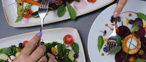 A dining table with three plates of food, each with a variety of vegetables and garnishes.