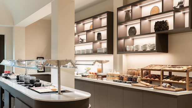 A modern breakfast bar with a variety of food items and a display of decorative plates and bowls. - AC Hotel by Marriott Wuerzburg (Würzburg)
