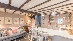 A cozy kitchen with a central island, a dining area with a sofa, and a staircase leading to an upper level. - Old Toffee Shop (Ambleside)