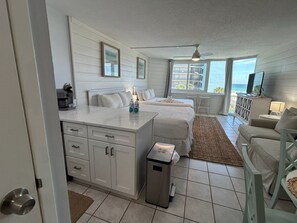 A room with a bed, a desk, a chair, a TV, and a view of the ocean. - 🏖️ Affordable Cozy Beachfront | FREE Beach Chairs | Early 3PM Check-In (Panama City Beach)