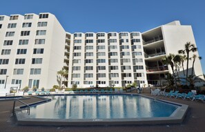 A hotel with a large pool, multiple balconies, and palm trees. - 🏖️ Affordable Cozy Beachfront | FREE Beach Chairs | Early 3PM Check-In (Panama City Beach)