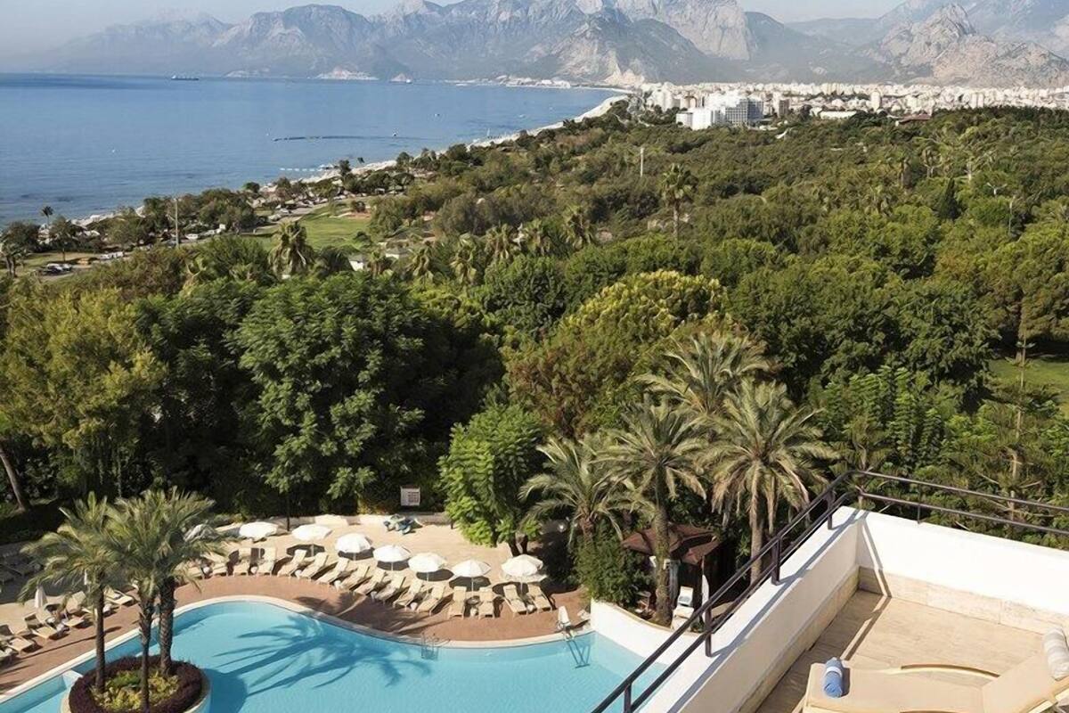 A rooftop pool with lounge chairs and a view of the sea and mountains.