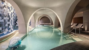 A swimming pool with arched ceilings and lounge chairs.
