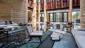 A spacious lobby with a modern design, featuring a large seating area, a glass coffee table, and a unique architectural column structure.
