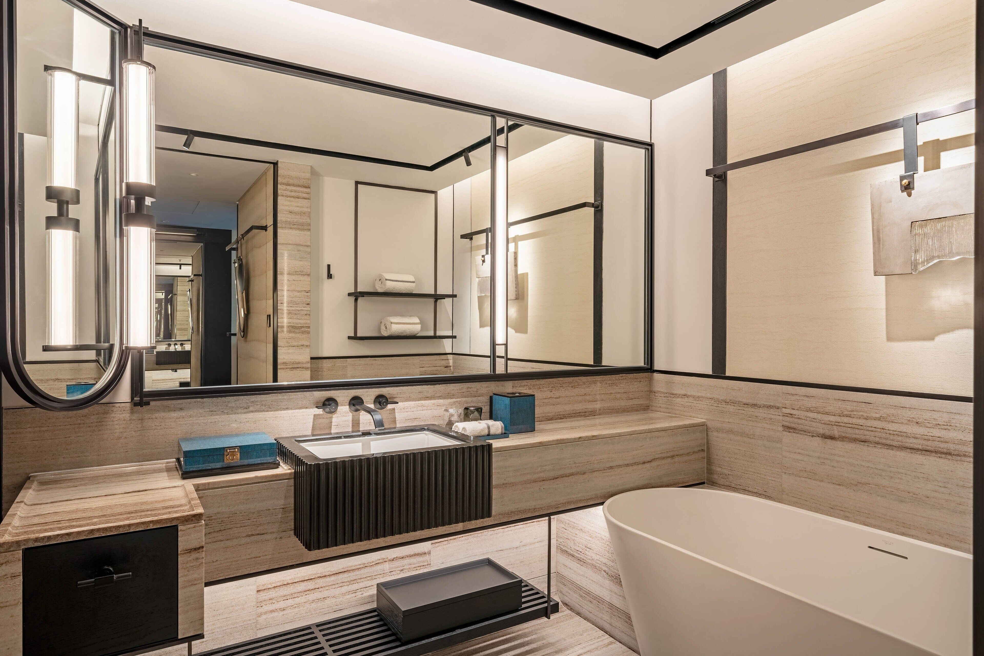 A modern bathroom with a large mirror, a bathtub, a sink with a vanity, and a towel rack.
