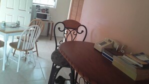 A dining area with a table, chairs, a telephone, and a microwave.
