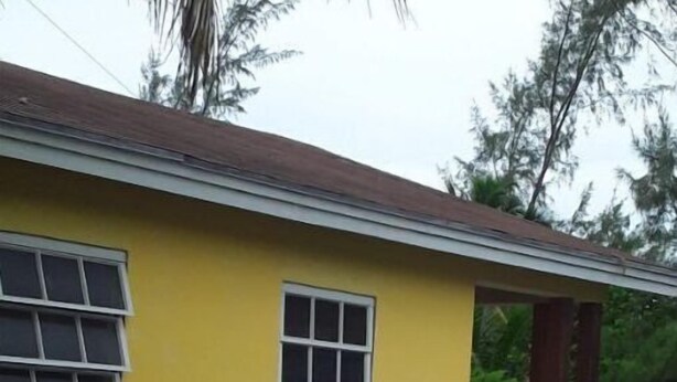 A yellow building with a small porch and a window.