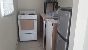 A compact kitchen with a stove, oven, refrigerator, and a small countertop.