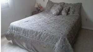 A bedroom with a bed, pillows, a nightstand, and a lamp.
