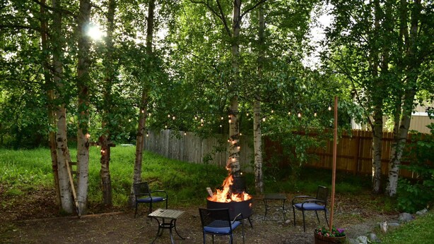 An outdoor patio area with a fire pit, two metal chairs, and a table.