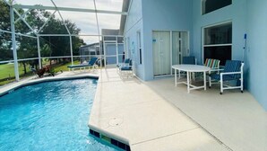Un espace aménagé au bord de la piscine, avec un patio couvert, des chaises longues et une table.