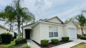 A single-story house with a front entrance, a garage, and a small front yard with landscaping. - Private Pool - TV in all Bedrooms - Newly renovated - Golf View (Haines City)