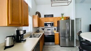 A modern kitchen with wooden cabinets, stainless steel appliances, and a white countertop. - Private Pool - TV in all Bedrooms - Newly renovated - Golf View (Haines City)