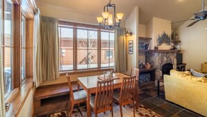 A dining area with a wooden table and chairs, a patterned rug, and a fireplace. - Mountain Retreat | Fire Pit | 3 Blocks off Main St. (Grand Lake)