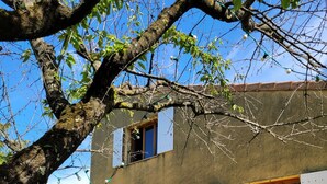 Un bâtiment doté d’un toit plat, de volets blancs et d’un petit patio avec une table et des chaises.