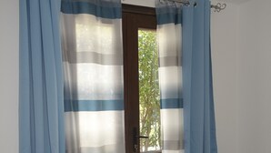 A room with a bed, a nightstand, and a window with curtains. - Holidays at Hydrangea Villa (San Teodoro)