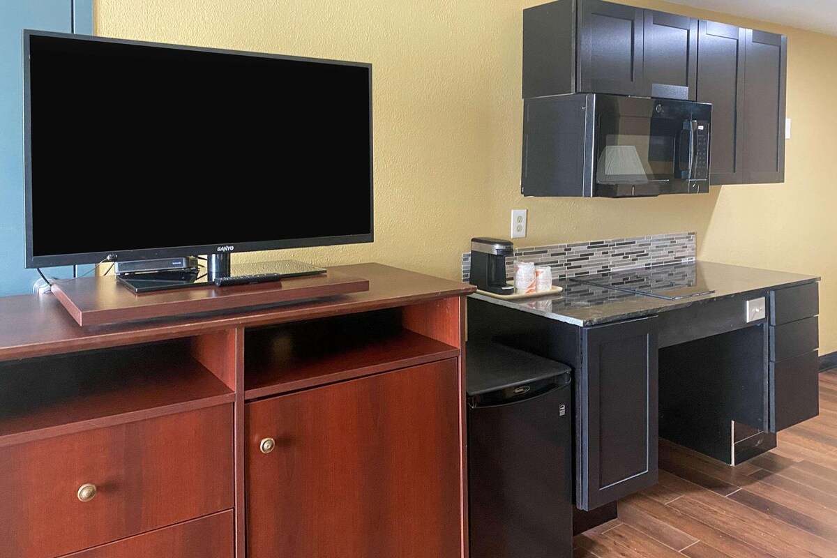 A compact kitchenette with a flat-screen TV, a microwave, and a coffee maker on a countertop.
