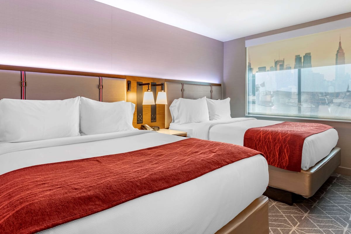 A hotel room with two beds, a city view, and a modern design.