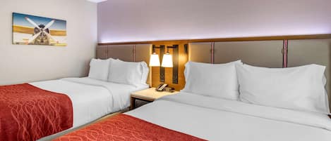 Een hotelkamer met twee bedden, een nachtkastje met een lamp en een schilderij van een vliegtuig aan de muur.