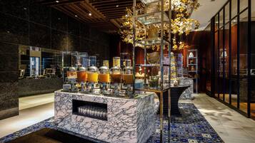 A modern lobby with a marble reception desk, glass display cases, and a chandelier.