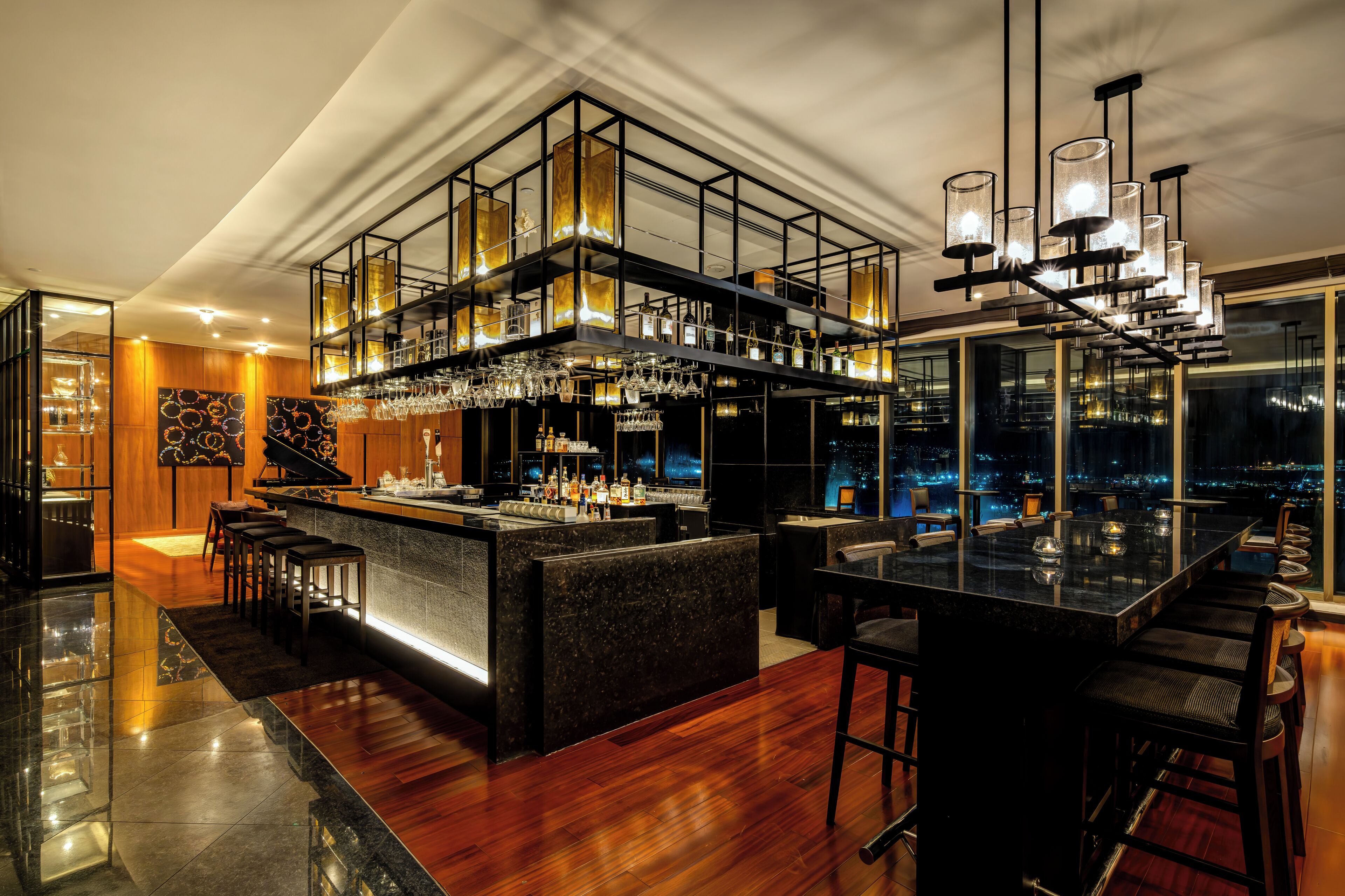 A modern bar area with a high bar counter, multiple seating options, and a city view.