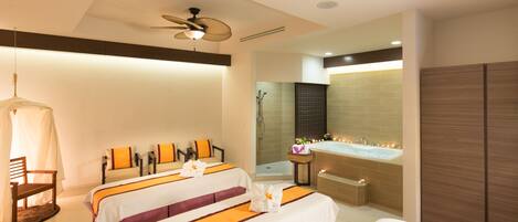 A hotel room with three beds, a sitting area, a bathtub, and a shower.