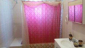 A bathroom with a shower curtain, a sink, and a mirror. - Agatha's Home In Paradise  (Westmoreland Parish)