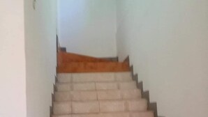 A staircase with a beige carpeted landing and a plain white wall. - Agatha's Home In Paradise  (Westmoreland Parish)