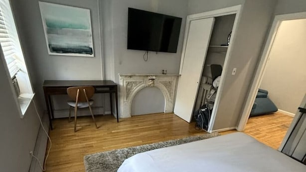 Une chambre à coucher comprenant un lit, un bureau, une chaise, une télévision, une cheminée et une armoire.