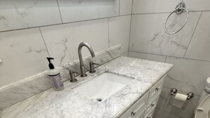 Une salle de bain avec un lavabo en marbre, des toilettes et un porte-serviettes.