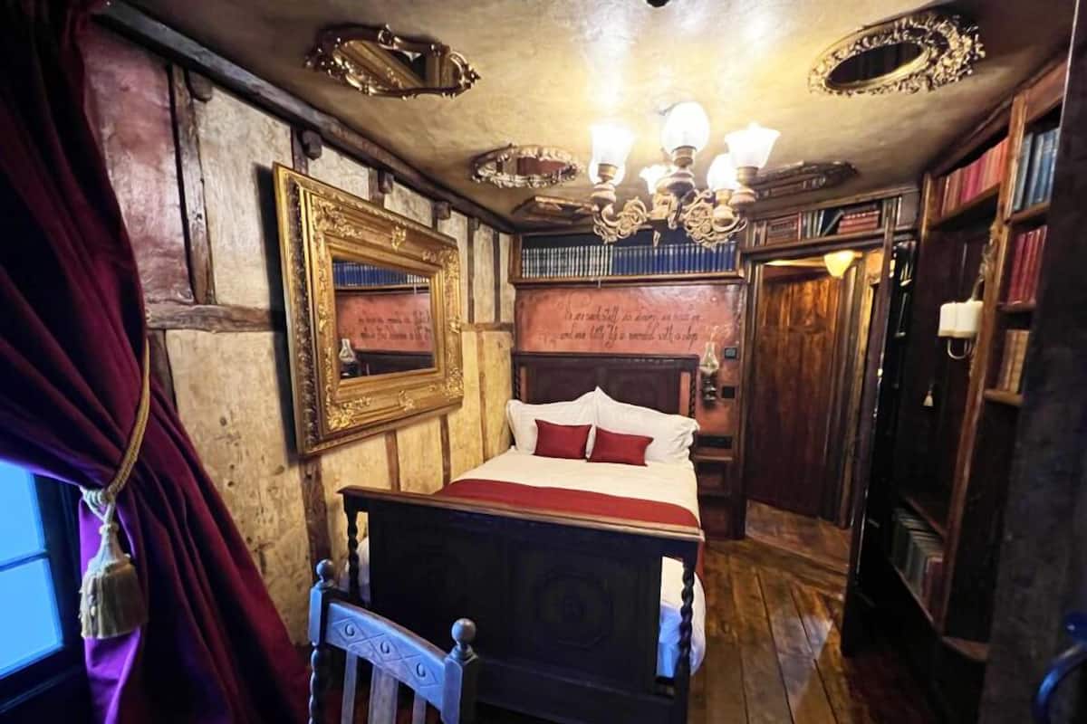 A traditional room with a wooden bed, a chandelier, and a bookshelf.